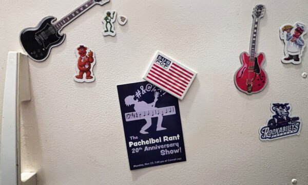 postcard on the freezer door of a white refrigerator, held on by an American Flag SubPop magnet. Other magnets are guitars, muppets, and the Jackson Rockabillies baseball team